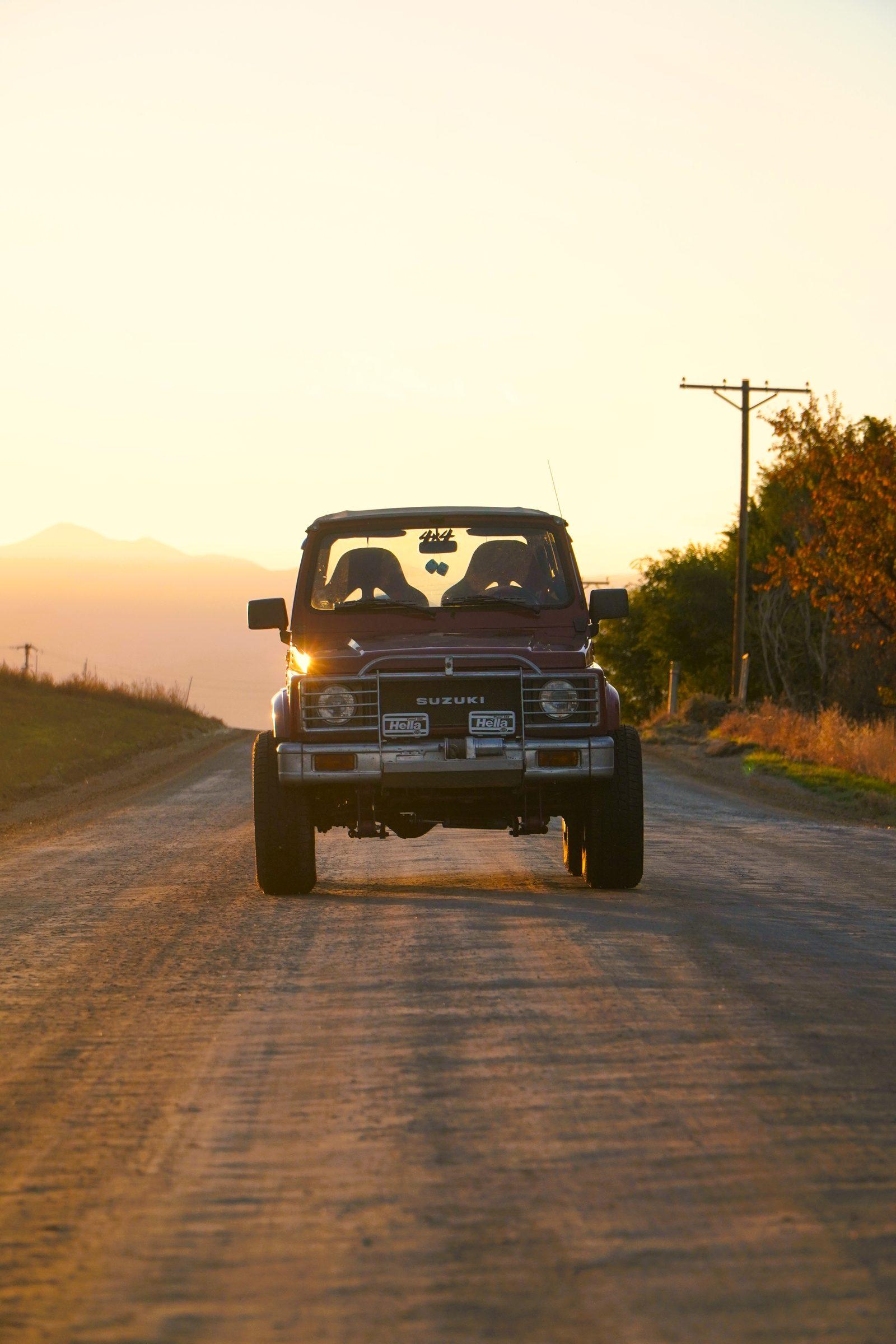 Suzuki Samurai on a dirt road at sunset