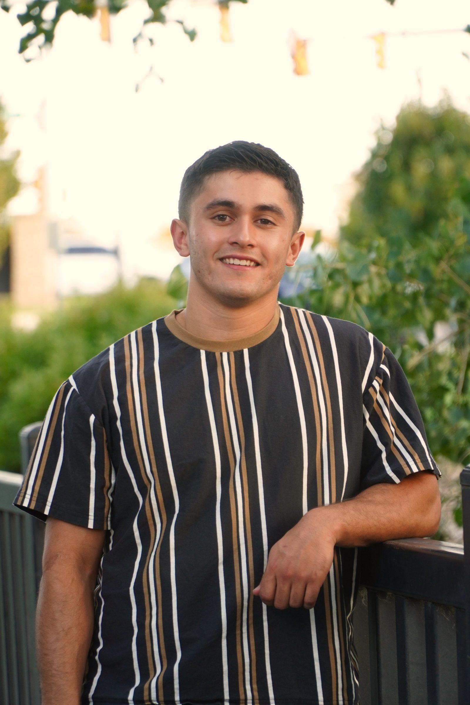 Senior portrait leaning on a deck railing, smiling