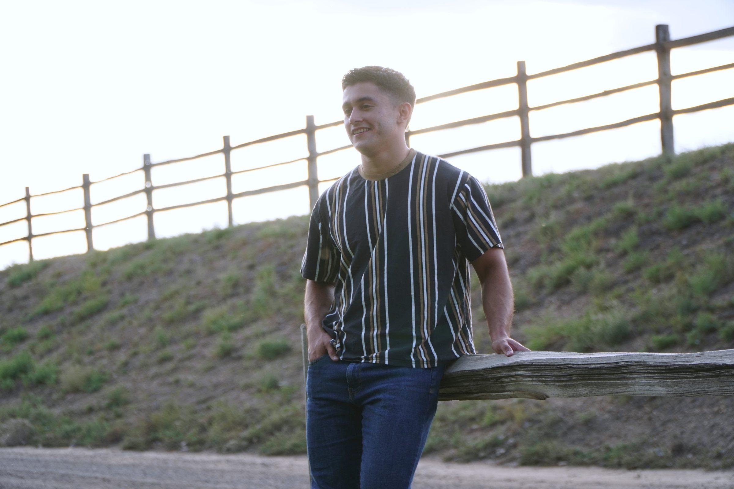Senior portrait leaning on a wooden fence at golden hour