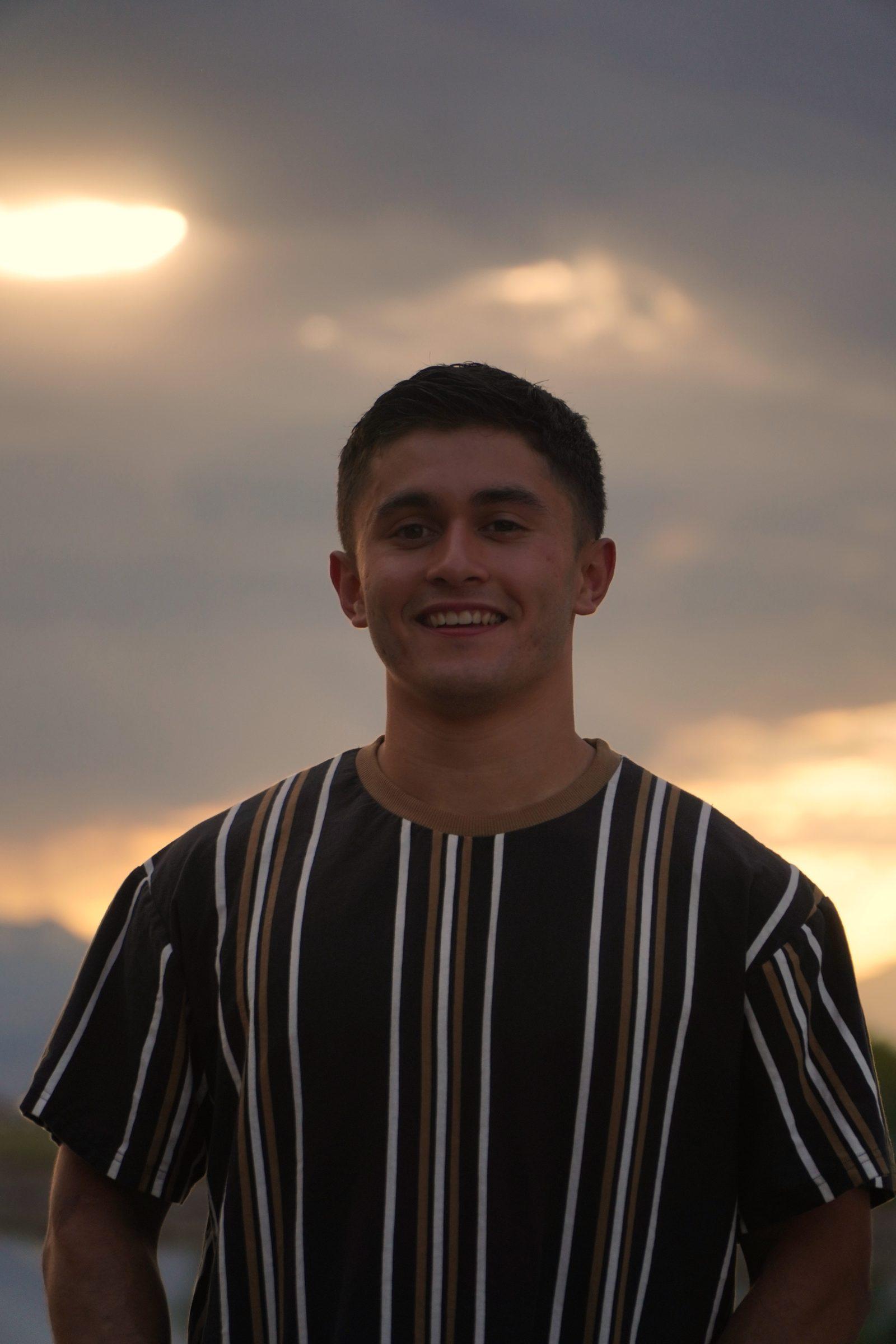 Senior portrait against a dramatic sunset sky