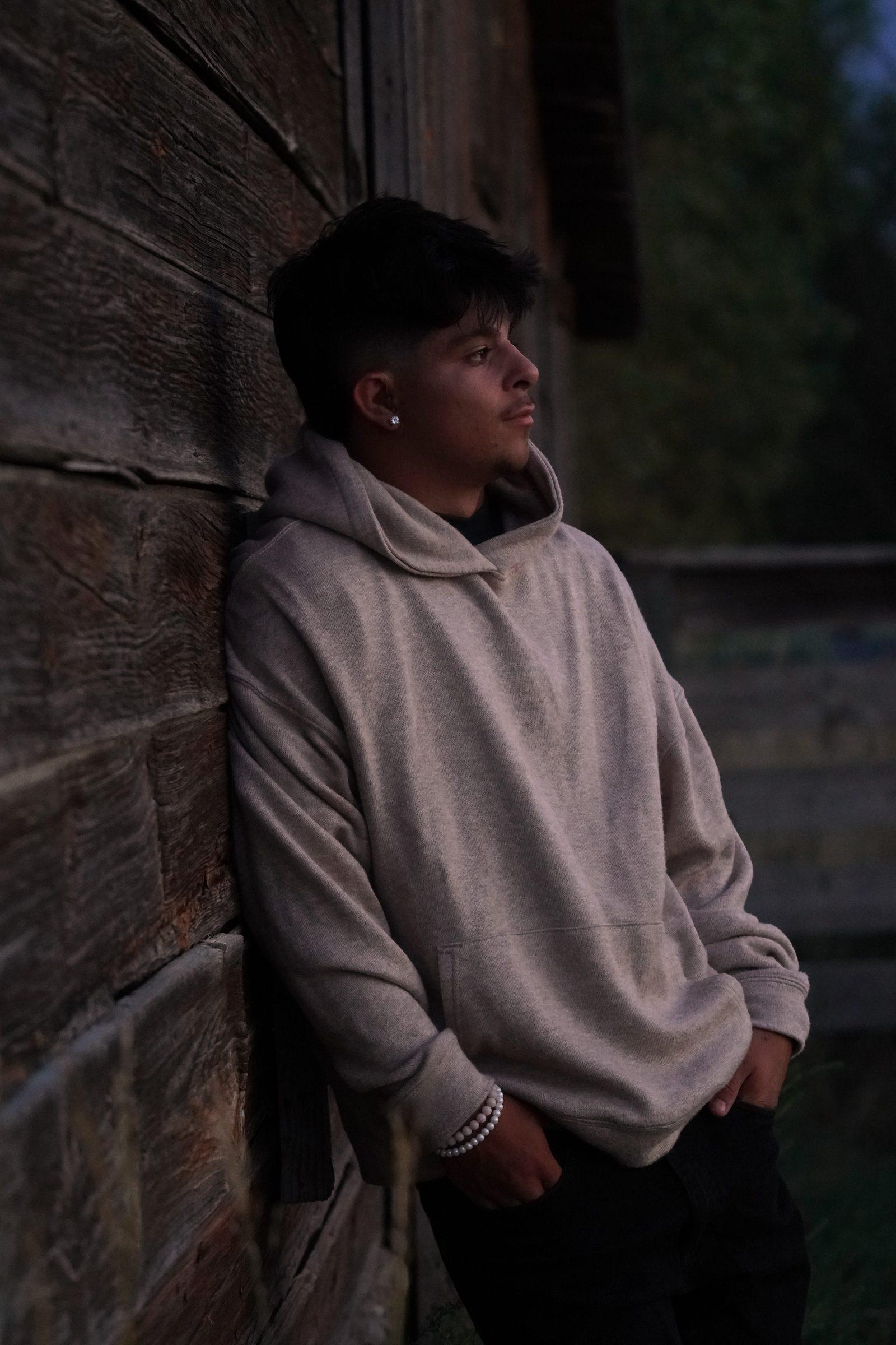 Senior portrait leaning against a rustic wooden wall